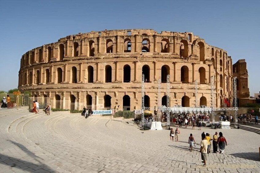 An ancient amphitheater with multiple levels of arches and a central stage area. 5