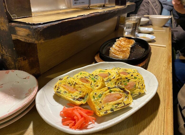 A plate of rolled omelettes with vegetables and a side of carrot shreds. 4