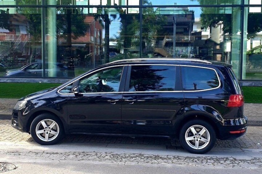 A black car parked on a street with a modern building in the background. 2