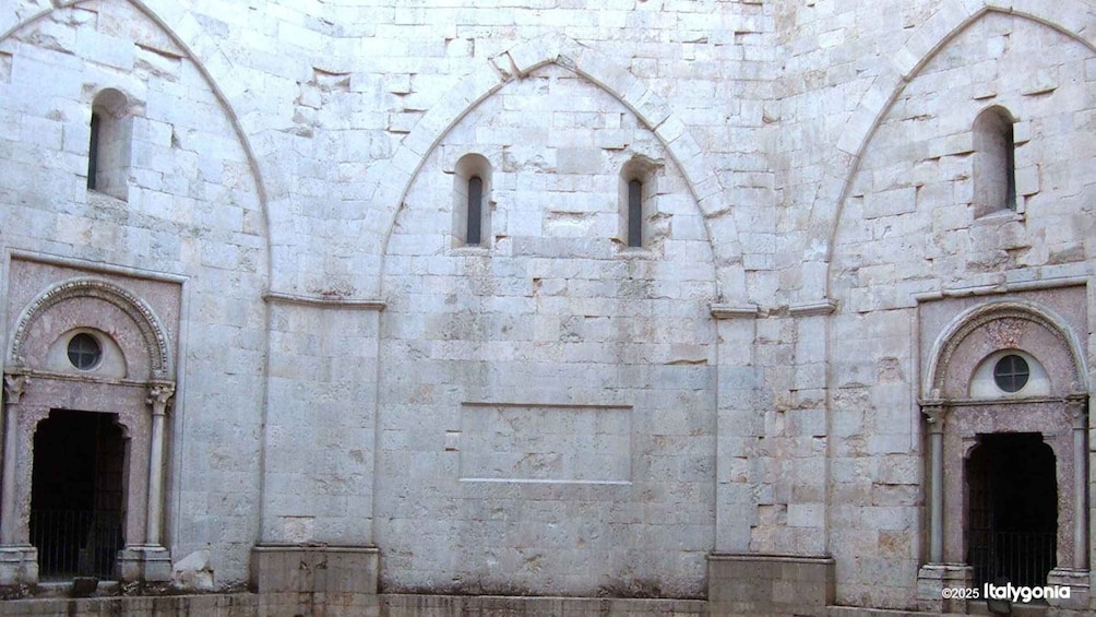 A historic stone building with arched doorways and windows. 1
