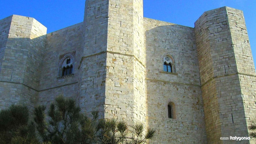 A historic stone castle with two visible towers and arched windows. 5