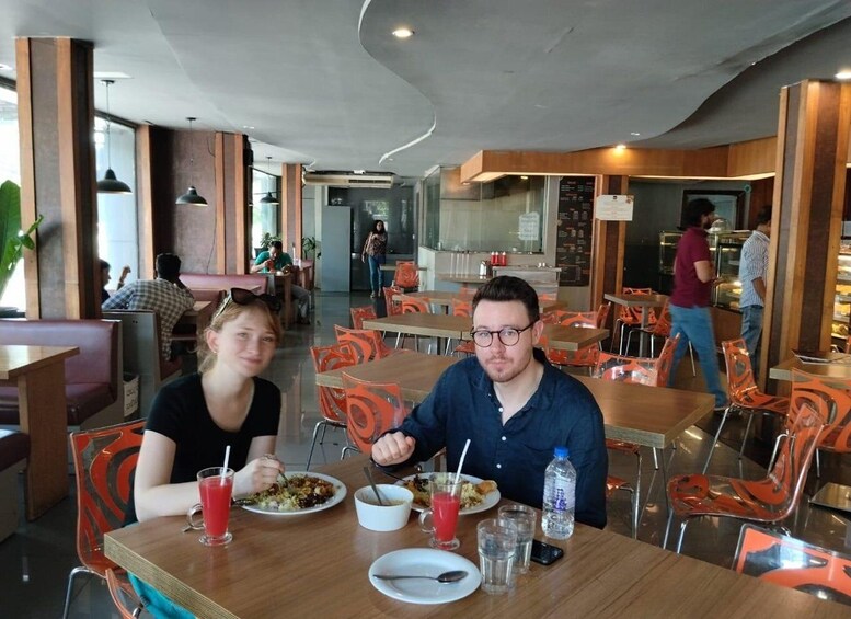 A restaurant with wooden tables and orange chairs, people dining, and a counter with a menu. 3