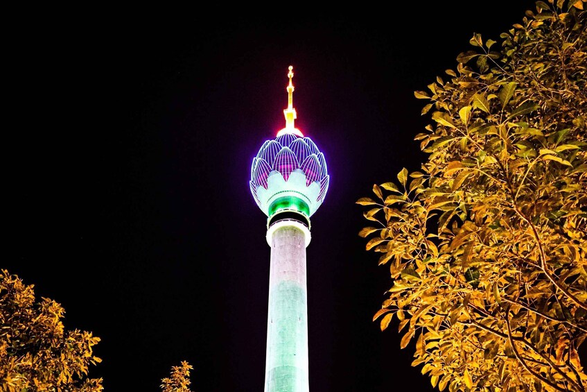A brightly lit tower with a spherical top, surrounded by trees. 4