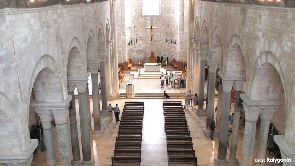 A cathedral interior with rows of pews, a central altar, and a crucifix above. 2