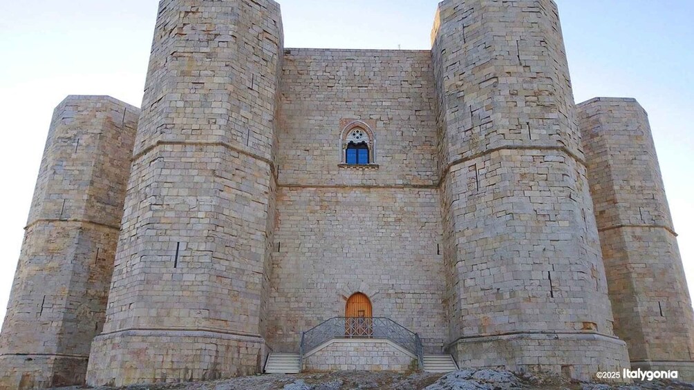 A large stone castle with two prominent towers, a central arched window, and a wooden door. 3