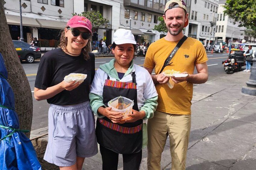 Three people standing on a sidewalk, holding food. 3
