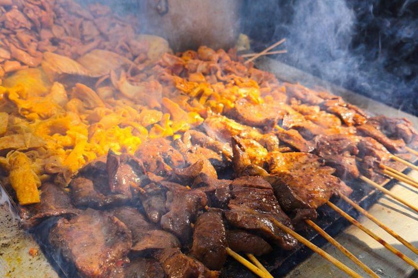 A variety of meats being grilled on skewers, with visible smoke and char marks. 5