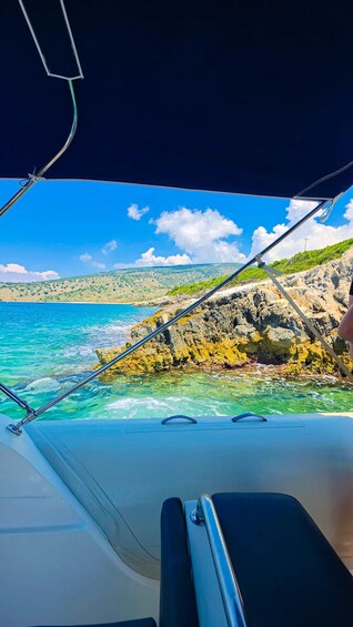 A boat's interior with a view of a rocky coastline and clear blue sea. 3