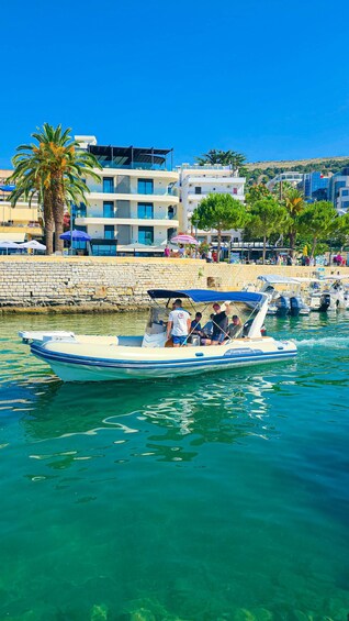 A boat on clear turquoise water, a stone wall, and modern buildings with balconies. 2