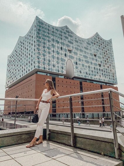 A woman in white standing on a staircase with a modern building featuring a grid of windows in the background. 5