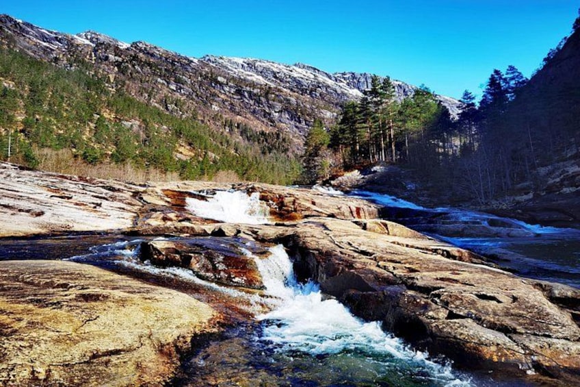 Un río que fluye sobre rocas, un paisaje montañoso y un cielo azul despejado. 3