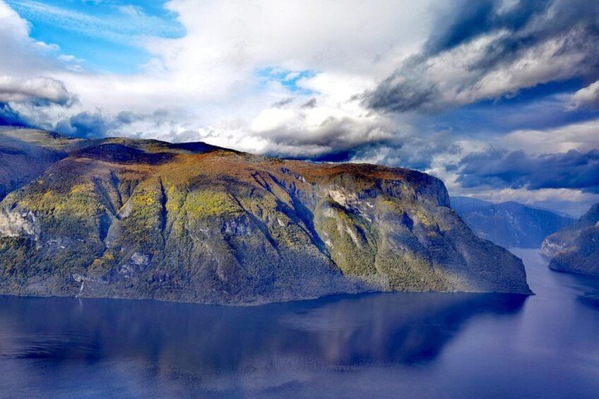 A mountain with a lake in the foreground and a cloudy sky. 5