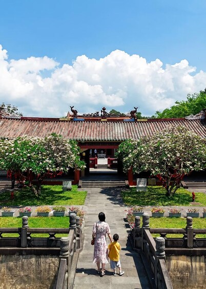 A traditional building with a tiled roof and ornate decorations, a pathway leading to it, and blooming trees. 4