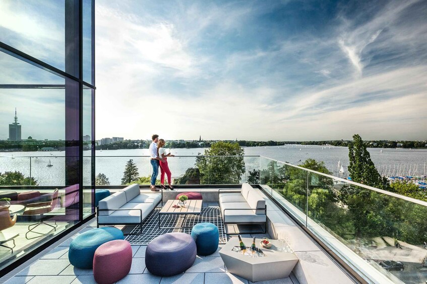 A modern rooftop terrace with seating and a view of a river. 1