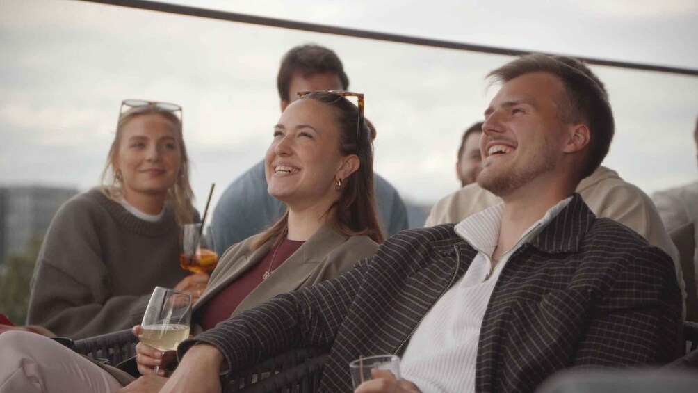 A group of people sitting outdoors, holding drinks. 5