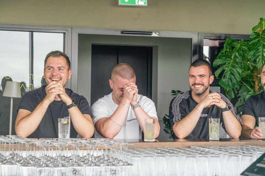 Three men sitting at a table with glasses and a plant in the background. 4