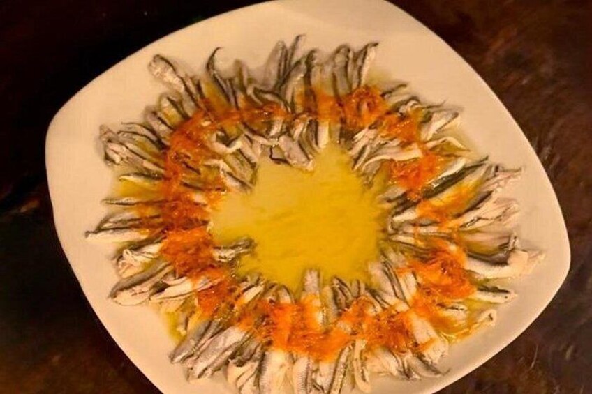 Un plato de comida con salsa amarilla en el centro y pescado dispuesto en un círculo. 2