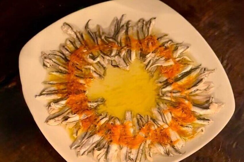 Un plato de sardinas dispuestas en un círculo con salsa amarilla en el centro. 3