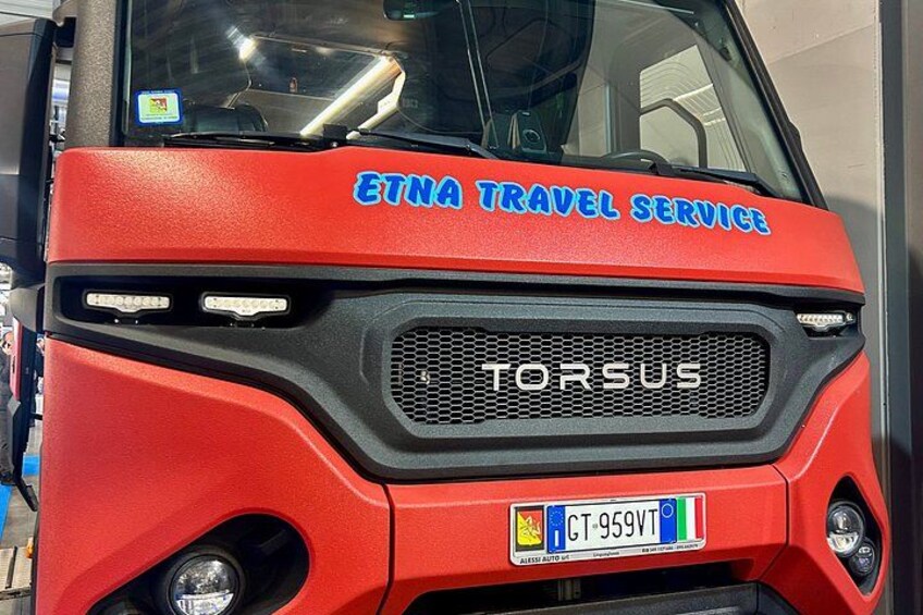 En röd buss med texten ”ETNA TRAVEL SERVICE” och ”TORSUS” på framsidan. 3