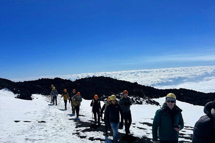 En grupp människor vandrar på ett snötäckt berg under en klar himmel. 1
