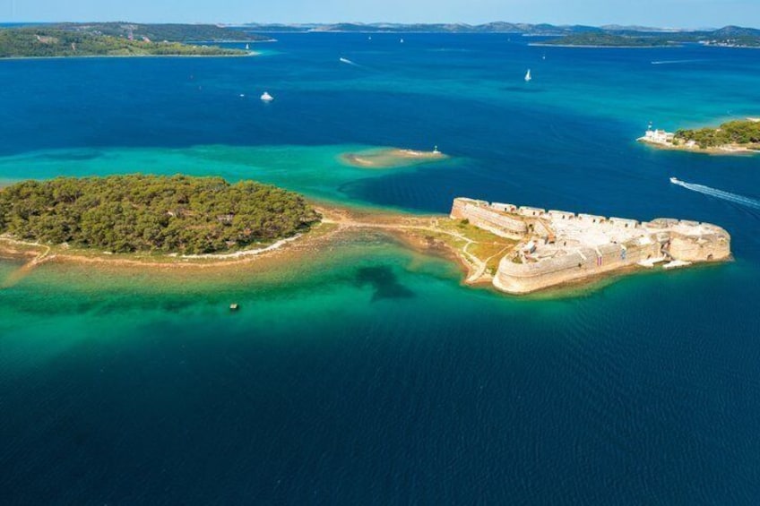 Luftaufnahme einer Küstenbefestigung, umgeben von türkisblauem Wasser und einer kleinen Insel mit dichter Vegetation. 3