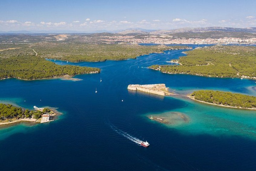 A coastal landscape with a large body of water, a peninsula, and a distant city. 2