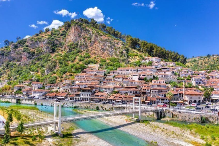 A coastal town with terraced houses, a bridge, and a clear blue sea. 1