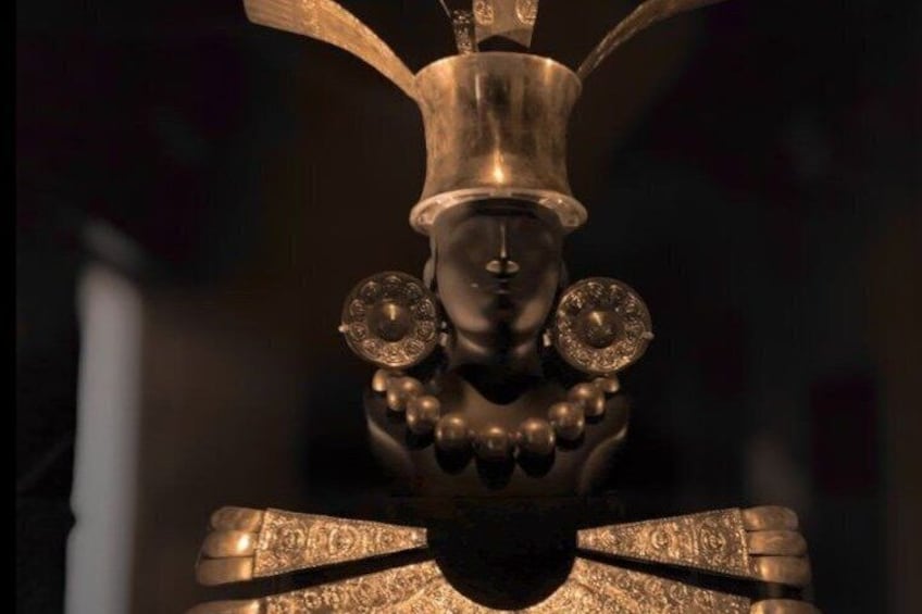 A bronze statue with a detailed headdress and ornate decorations. 1