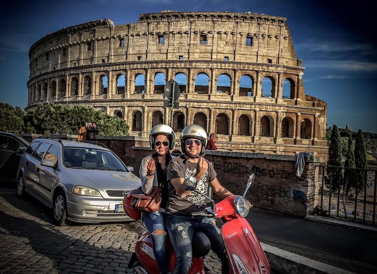 A couple on a red Vespa in front of the Colosseum. 5