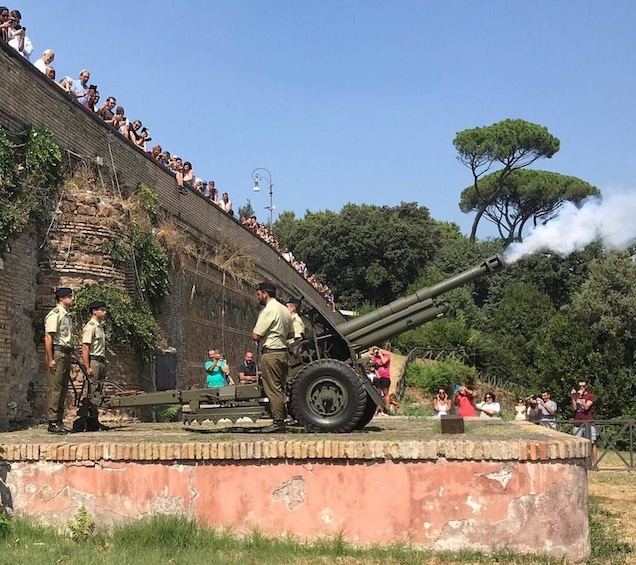 A cannon on display with a crowd of people observing it. 3