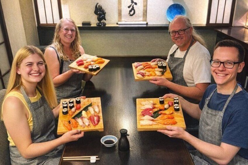 Fire personer holder sushibakker ved et bord. 1