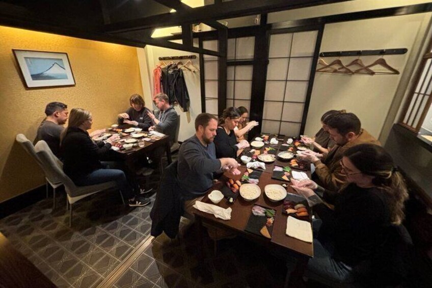 En gruppe mennesker sidder omkring et rundt bord på en restaurant med udsigt over bybilledet. 2
