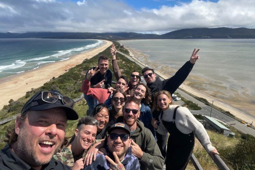 Un grupo de personas en un mirador costero, con una playa y el océano al fondo. 3