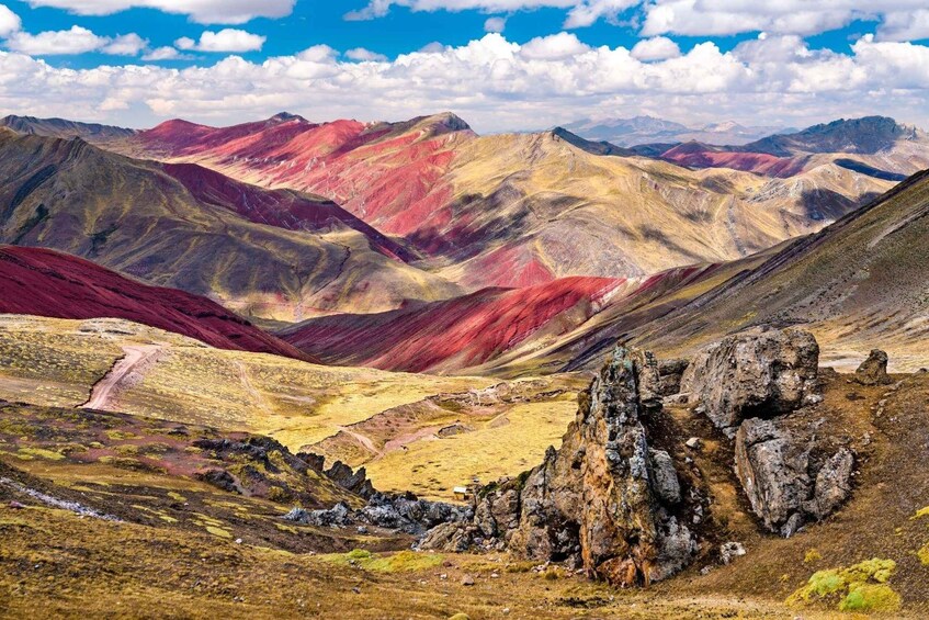 A mountainous landscape with red and yellow hues, rocky outcrops, and a clear sky. 5