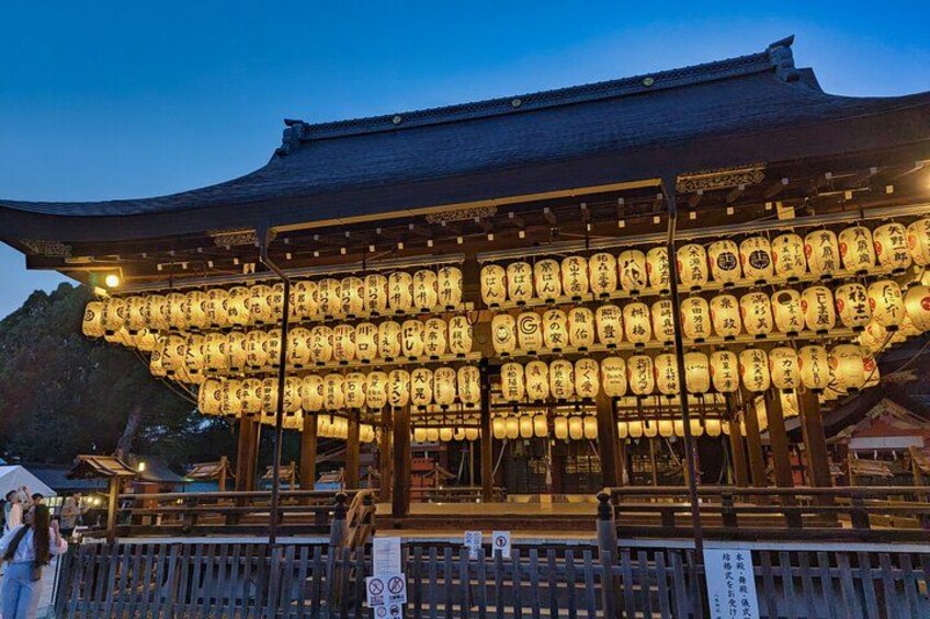 Un edificio japonés tradicional con faroles iluminados y una valla de madera al frente. 2