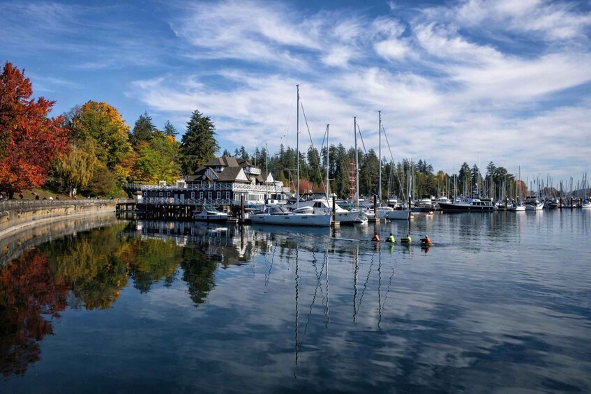 A marina with boats, a dock, and autumn trees reflecting on the water. 4
