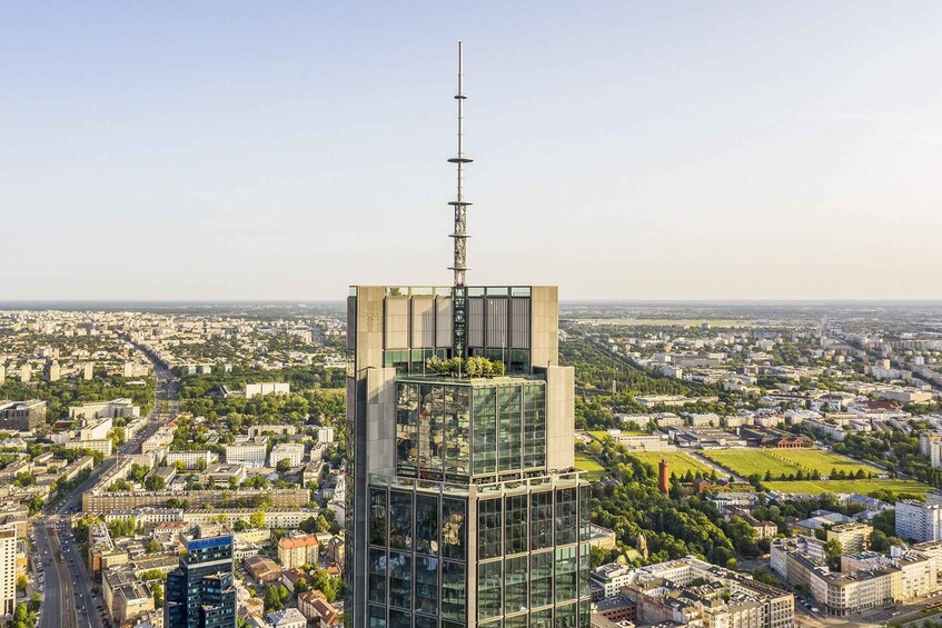 A high-rise building with a communication tower, surrounded by a cityscape and greenery. 5