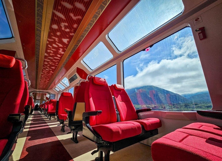 A train interior with red seats and large windows. 1