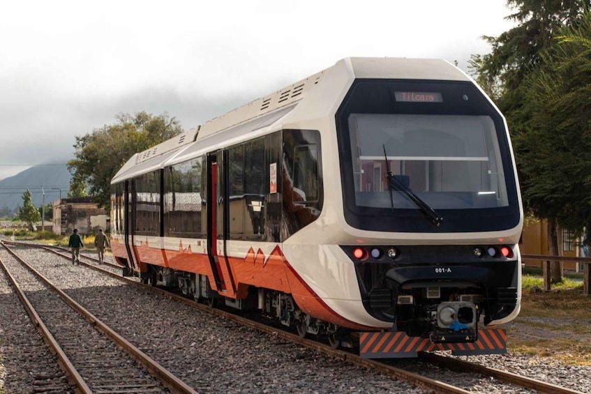 A modern train with 'Tilcara' on the front, traveling on tracks with a mountainous backdrop. 3