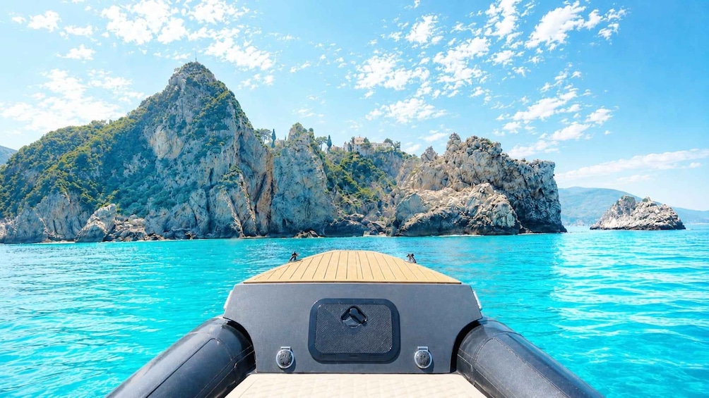 A boat's deck with a view of rocky cliffs and clear turquoise water. 1
