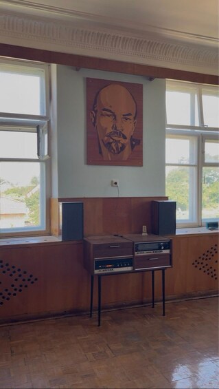 A room with a wooden cabinet, two speakers, and a painting on the wall. 4
