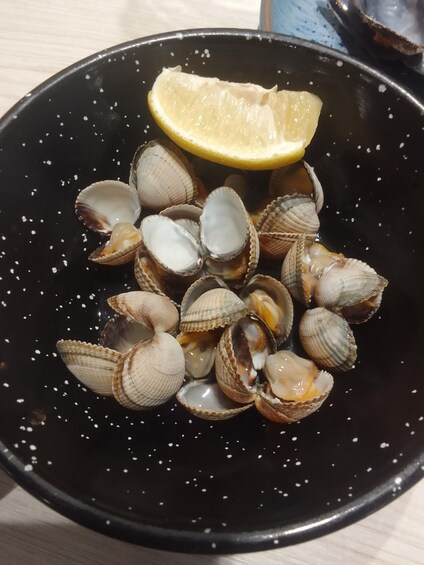 A black pan with clams and a lemon wedge. 2
