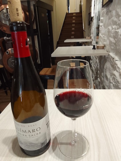 A bottle of wine and a glass of red wine on a table in a restaurant. 1