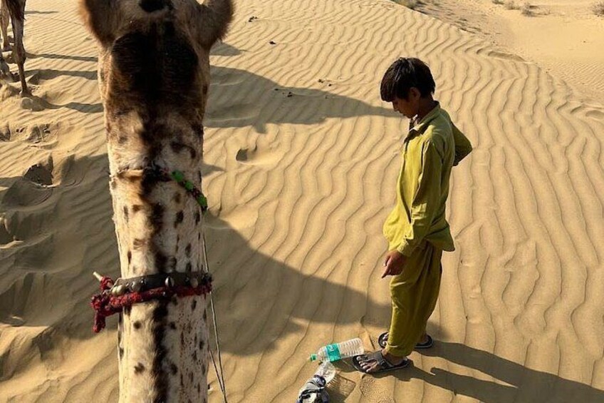 A camel with a rope around its neck, a person in traditional attire, and sand dunes in the background. 5