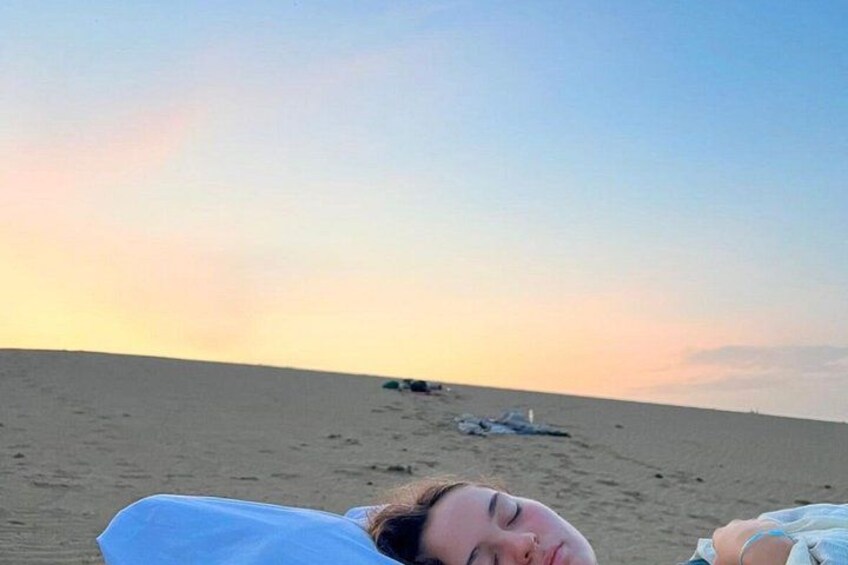 A beach with a sunset in the background and a person lying down. 1