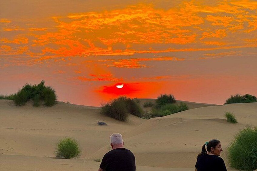A desert landscape with sand dunes and sparse vegetation during sunset. 4