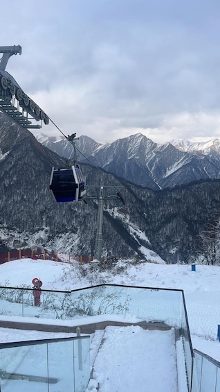 A cable car in motion, a snowy mountain landscape, and a ski lift structure. 5