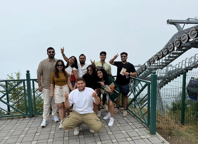 A group of people posing on a bridge with a roller coaster in the background. 2
