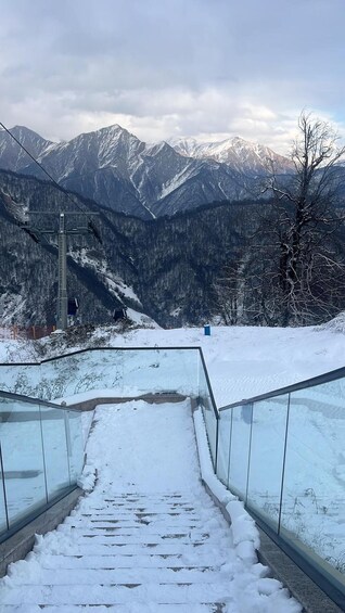 A snow-covered staircase leading to a mountain overlook with a view of snow-capped peaks. 3