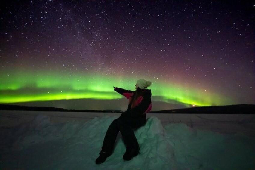 En person sidder på sneen med nordlys i baggrunden. 3